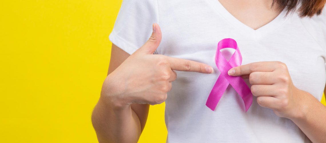 Breast cancer month, a woman in a white T-shirt with a satin pink ribbon on her chest, a symbol for breast cancer awareness campaign in October